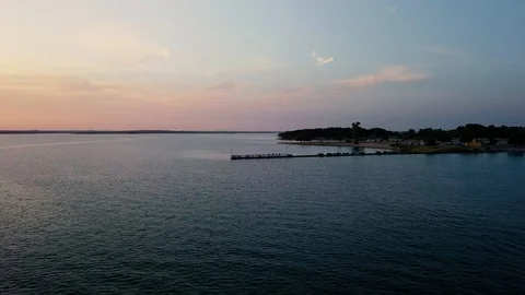 Flying over waters during a sunset getting closer to a dock Stock Footage 93632806