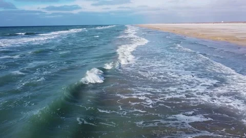 Flying over the waves at the sandy beach against the blue sky Stock Footage 238894685