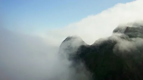 Flying over white clouds above hills at sea shoreline reveals an isle at horizon Stock Footage 169092891