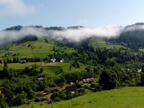 Flying over white clouds and little village Stock Photos