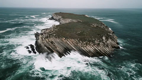 Flying over a wild stone island in the midst of a raging ocean Stock Footage 297123721