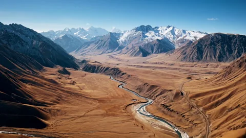 Flying over a wild water stream among mountains and mountain road Stock Footage 297091871