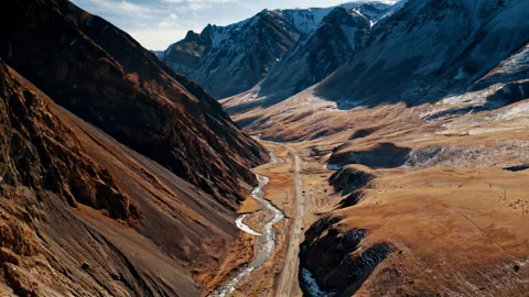 Flying over a wild water stream among mountains and mountain road Stock Footage 297127870