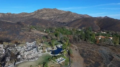 Flying over a wildfire destroyed home and hillside Stock Footage 100339567