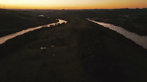 Flying over winding river at sunset amid green fields and forest. Stock Footage 233219801