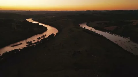 Flying over winding river at sunset amid green fields and forest. Stock Footage 233219836