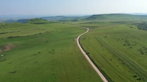 Flying over a winding road between green hills. Transylvania, Romania Stock Footage 194468234