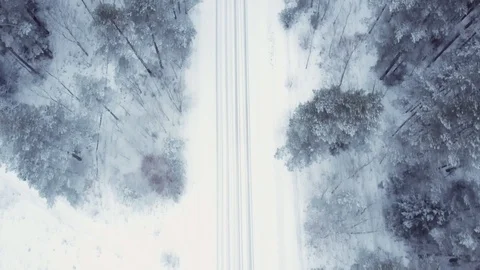 Flying over the winter forest and snow-covered road. It is snowing, frozen Stock Footage 101715792