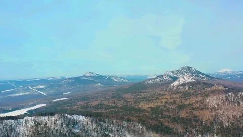 Flying over a winter forest and snow-capped mountains on a Sunny day Video stock 126097094