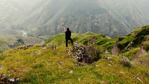 Flying over young man standing at the edge of the cliff Stock Footage 95540642