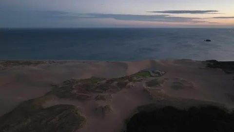 Flying parallel to coast over deserted sand dunes on beach before sunrise Stock-Footage 248307119