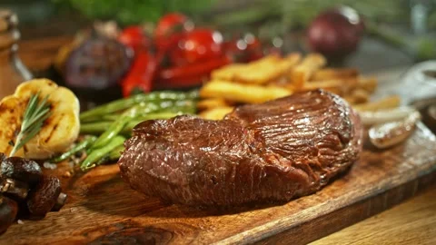 Flying piece of grilled beef steak falling on table Stock Footage 266995749