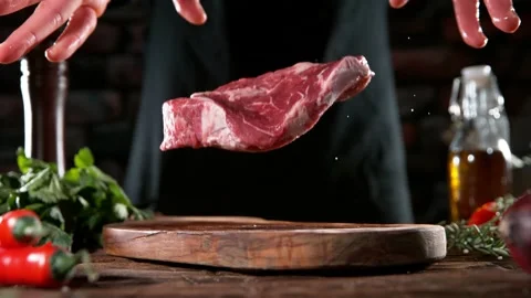 Flying piece of raw beef steak falling on table Stock Footage 169671574