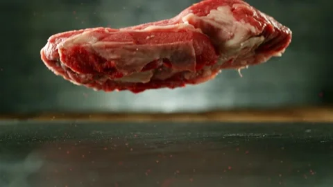 Flying piece of raw beef steak falling on table Stock Footage 235902861