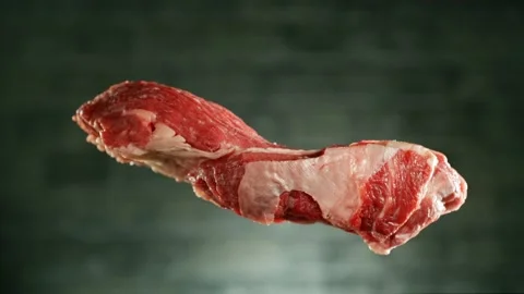 Flying piece of raw beef steak falling on table Stock Footage 235903074