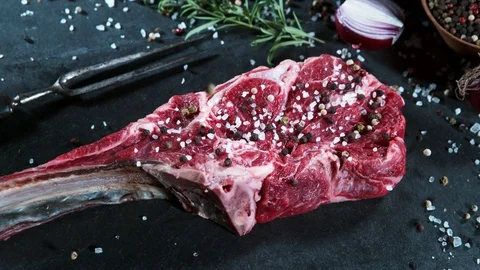 Flying piece of spices falling on raw beef tomahawk steak. Stock Footage 123549232