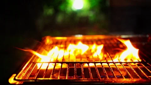 Flying pieces of beef meat pieces from a grill that has a lot of fire  Video stock 130097586