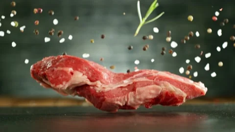 Flying pieces of raw beef steak falling on table Stock Footage 235905475