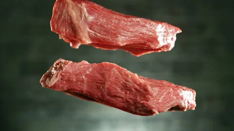 Flying pieces of raw beef steaks falling on table Stock Footage 235902865