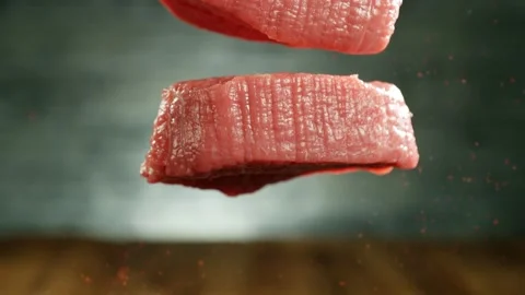 Flying pieces of raw beef steaks falling on table Stock Footage 235904069