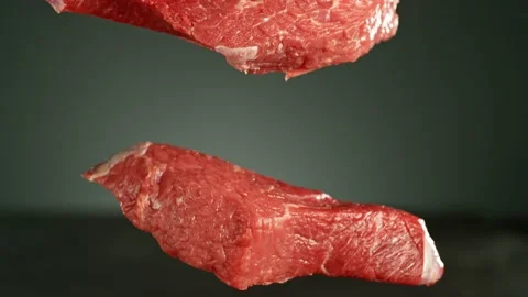 Flying pieces of raw beef steaks falling on table Stock Footage 237316619