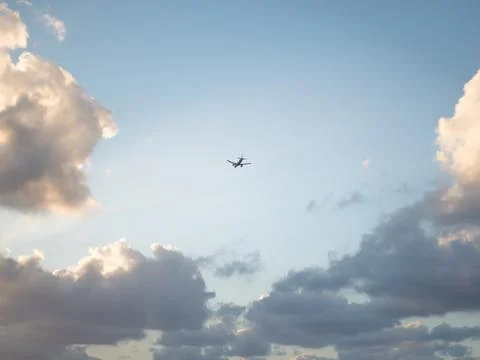 Flying plane in the sky with clouds at sunset as a background Stockfoto's