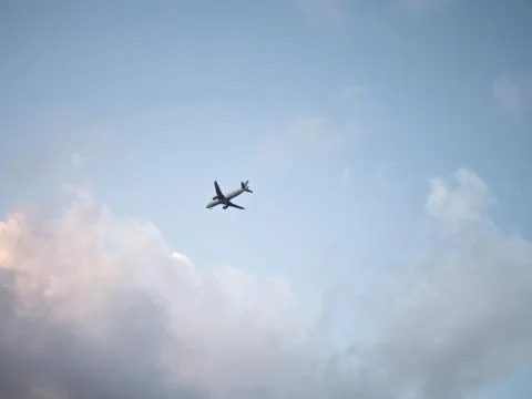 Flying plane in the sky with clouds at sunset as a background Stockfoto's