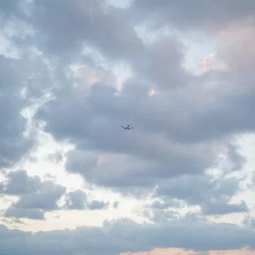 Flying plane in the sky with clouds at sunset as a background Stockfoto's