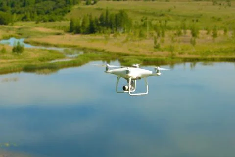 Flying quadrocopter "Phantom" on the background of the summer lake Stock Photos