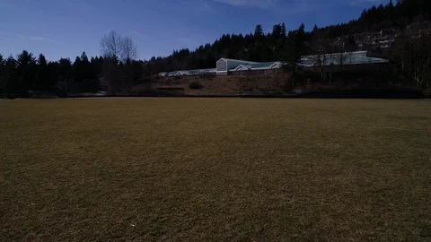 Flying Quickly Lowly Over A Field Towards A Hill And A Small School Building Stock Footage 104783108