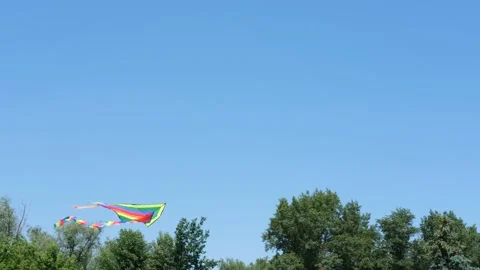 Flying rainbow colored kite against background blue sky on sunny day in summer. Video stock 158387062