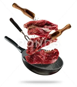 Flying raw steaks with cooking ingredients from pan Stock Photos