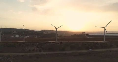 Flying by a raw of wind turbines during a sunset 4K Stock Footage 103792827