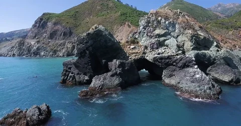 Flying reverse from sea cave arch to panoramic view of Big Sur, California Stock Footage 76484484