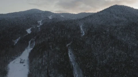 Flying up the ridge of a snow dusted mountain with a broken ski lift below 스톡 동영상 122690937