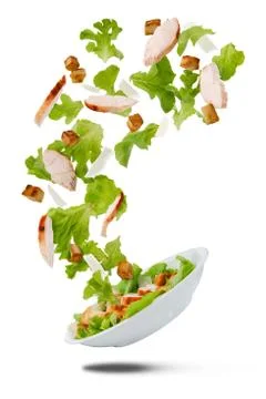 Flying salad isolated on white. Caesar with chicken and thrown up ingredients Stock Photos