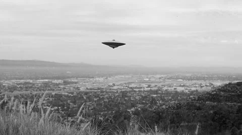 FLYING SAUCER / UFO  HOVERS OVER A VALLEY Stock Footage