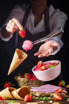 Flying scoop with strawberry Ice cream going to fill levitating wafer cone Stock Photos