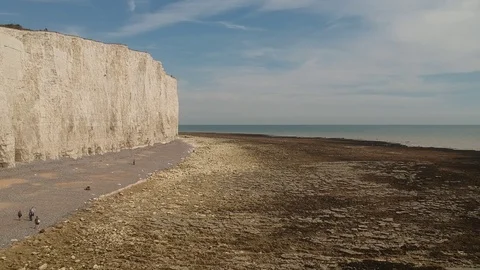 Flying shot besides white cliffs revealing sea and lighthouse in the background Stock Footage 94483979