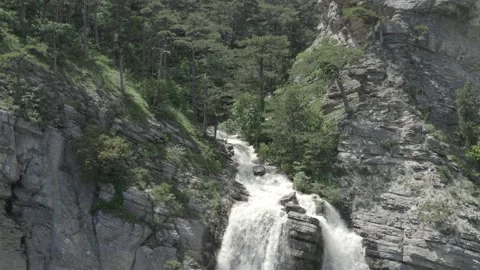 Flying shot over the mountains, pine forest to the waterfall Видео 156173379