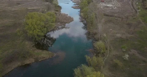 Flying up the side of a hill along a small pond with trees and matching houses Stock Footage 129738933