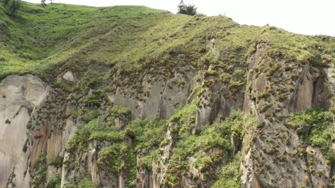 Flying sidewards to show more of a large rocky grey and red coloured cliff Stock Footage 142755177