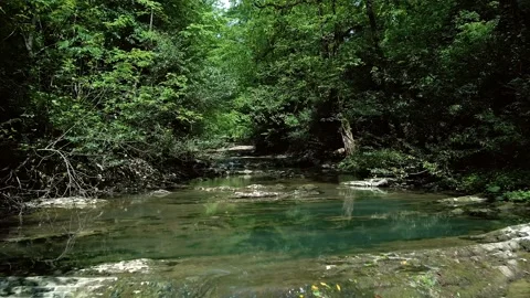 Flying slowly and low on a drone along the river from the waterfall among the Video stock 235339322
