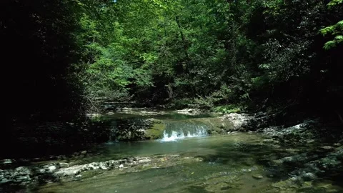 Flying slowly and low on a drone along the river from the waterfall among the Video stock 235339352