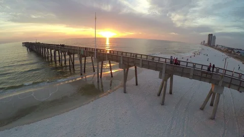 Flying slowly backwards down the beach away from the pier viewing the sunset. Stock Footage 90562793