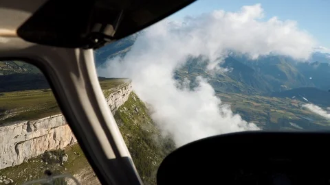 Flying small aircraft, cabin view. Clouds, mountains, cliff in airplane window. Stock Footage 125738137