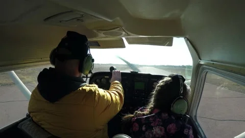 Flying in a small light plane. A man pilot with a girl child in the cabin  Stock Footage 169858116