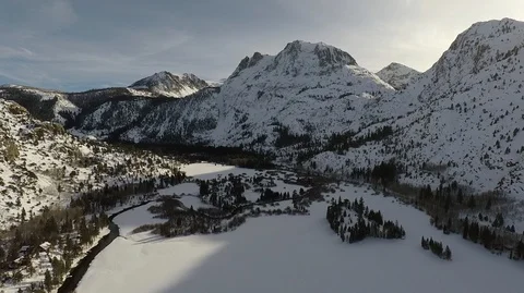 Flying in a snow valley at a snow capped mountain aerial view Stock Footage 98499726