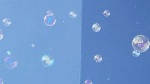 Flying soap bubbles against blue sky in sunlight, colorful bubbles floating Stock Footage 341436944