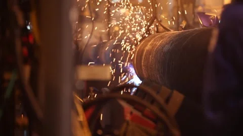 Flying Sparks from Automated Welding on Rotating Steel Pipe in Factory Stock Footage 341860484